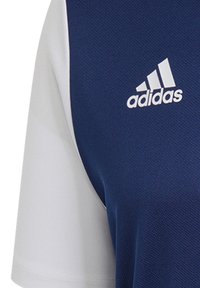 Adidas-Sporttrikot mit einem marineblauen Körper, weißen kurzen Ärmeln, strukturiertem Stoff und einem auffälligen weißen Logo auf der Brust.