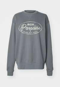 Grå hettegenser med rund hals, lange ermer, ribbestrikkede mansjetter og et sentralt trykk som leser "IRON Paradise MADE NOT BORN."