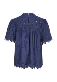 Mörkblå blus med puffärmar, prydd med broderade spetsdetaljer och utskurna mönster. Nyckelhålsstängning bak. Lättviktig tyg.
