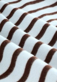 Tejido de punto con franjas onduladas alternas en marrón y blanco, mostrando una textura suave y un patrón detallado.