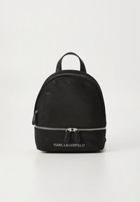 Svart ryggsäck med rundad design, matt material, silverfärgad dragkedja och präglade logodetaljer på ytan. Dubbel handtag för bärning.