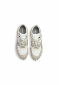 Baskets de sport beiges et blanches avec des accents gris, des panneaux texturés et des lacets beiges. Bout arrondi et semelle rembourrée.