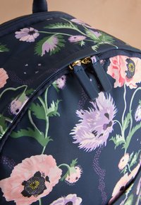Virágos hátizsák tengerészkék háttérrel, rózsaszín, lila és zöld növényi mintákkal. Tengerészkék cipzárral és arany színű fém kiegészítőkkel ellátva.