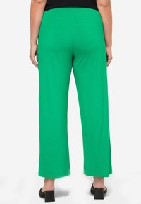 Gröna vida byxor i mjukt och stretchigt tyg, med hög midja och avslappnad passform, kombinerat med svarta klacksandaler.