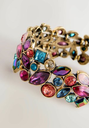 Gold-tone bracelet adorned with various colorful gemstones, including pink, blue, and purple, featuring intricate cut shapes and patterns.
