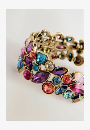 Kuldtooniga käevõru, millel on mitmesuguseid värvilisi vääriskive, sealhulgas roosa, sinine ja lilla, ning millel on keerukad lõikekujud ja mustrid.