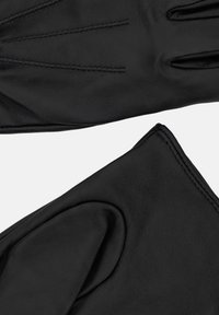 Melnas ādas cimdi ar trim dekoratīvām šuvēm augšpusē, gluda tekstūra un noapaļots aproces detaļa. Minimalistisks un slēgts dizains.