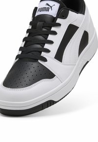 PUMA sneakers med en hvid læderoverdel med sorte accenter, perforeringer på tæerne og et lavt design. Sort gummisål.