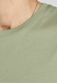 Zielona bawełniana koszulka z okrągłym dekoltem, o gładkiej fakturze i krótkich rękawach, prezentująca prosty, jednolity kolor.