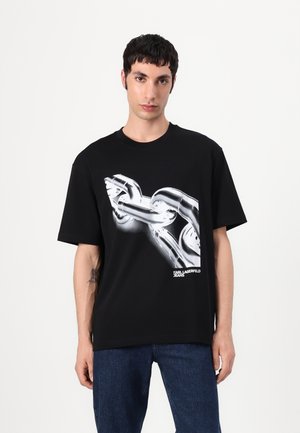 Zwarte katoenen T-shirt met een grafisch ontwerp van een zilveren ketting. Losse pasvorm met korte mouwen en een ronde halslijn. Merkl logo aan de onderkant.