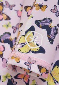 Ljust rosa tyg med ett fjärilsmönster i olika färger. Inkluderar ett vitt logopatch på mudden med sömnadsdetaljer.