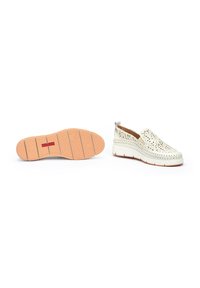 Zapatos slip-on perforados blancos con suela de goma y sutiles acentos en color marrón, que cuentan con una plantilla acolchada y un diseño liviano.