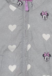 Šedá mikina na zip vyrobená z měkké tkaniny, zdobená bílými srdíčky a grafikou Minnie Mouse s růžovou mašlí. Zipová taháčka je fialová.