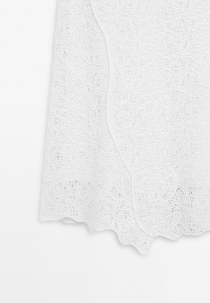 Weißer Spitzenrock mit intricatem Blumenmuster und gewelltem Saum. Hergestellt aus leichtem Material, verfügt über eine strukturierte Oberfläche und einen sanften Abschluss.