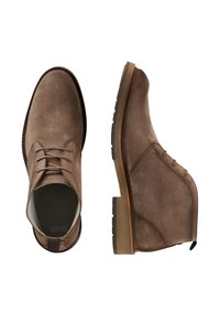 Stivaletti in suede marrone, alla caviglia, con lacci, punta arrotondata e suola in gomma. Presentano una linguetta sul tallone e dettagli di cucitura tono su tono.