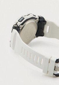 Weiße Silikon-Armbanduhr mit schwarzem Akzent; verfügt über eine silberne Rückseite aus Edelstahl und horizontale Rillen am Armband.