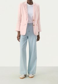 Blazer en lin rose clair à deux boutons, associé à un jean large bleu clair et des baskets blanches. Design simple et décontracté.