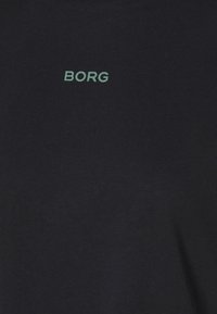 Granatowy t-shirt wykonany z bawełny, z małym zielonym logo "BORG" nadrukowanym na klatce piersiowej. Miękka tekstura, luźny krój.