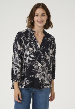 Blouse florale sombre à manches trois-quarts, avec un décolleté en V, fond marine et motifs de fleurs argentées et blanches. Tissu doux.