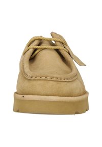 Foranbilde av en mokasinsko i lys mokka med tykke beige lisser og en lys brun gummisåle.