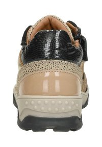 Beige en zwarte sneaker met een gestructureerde bovenkant, glanzende accenten en een gevoerde zool. Voorzien van een klittenbandsluiting en stippen detail.