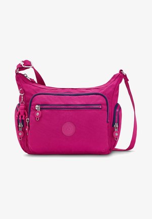 Sac bandoulière rose vif avec plusieurs compartiments zippés, une sangle réglable et un petit porte-clés singe attaché à la poche latérale.