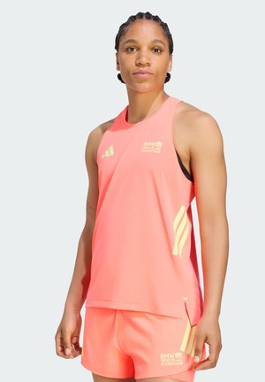 Atlet iført en klar koralfarvet BMW Berlin Marathon tanktop og matchende shorts, stående mod en ensfarvet lys baggrund.