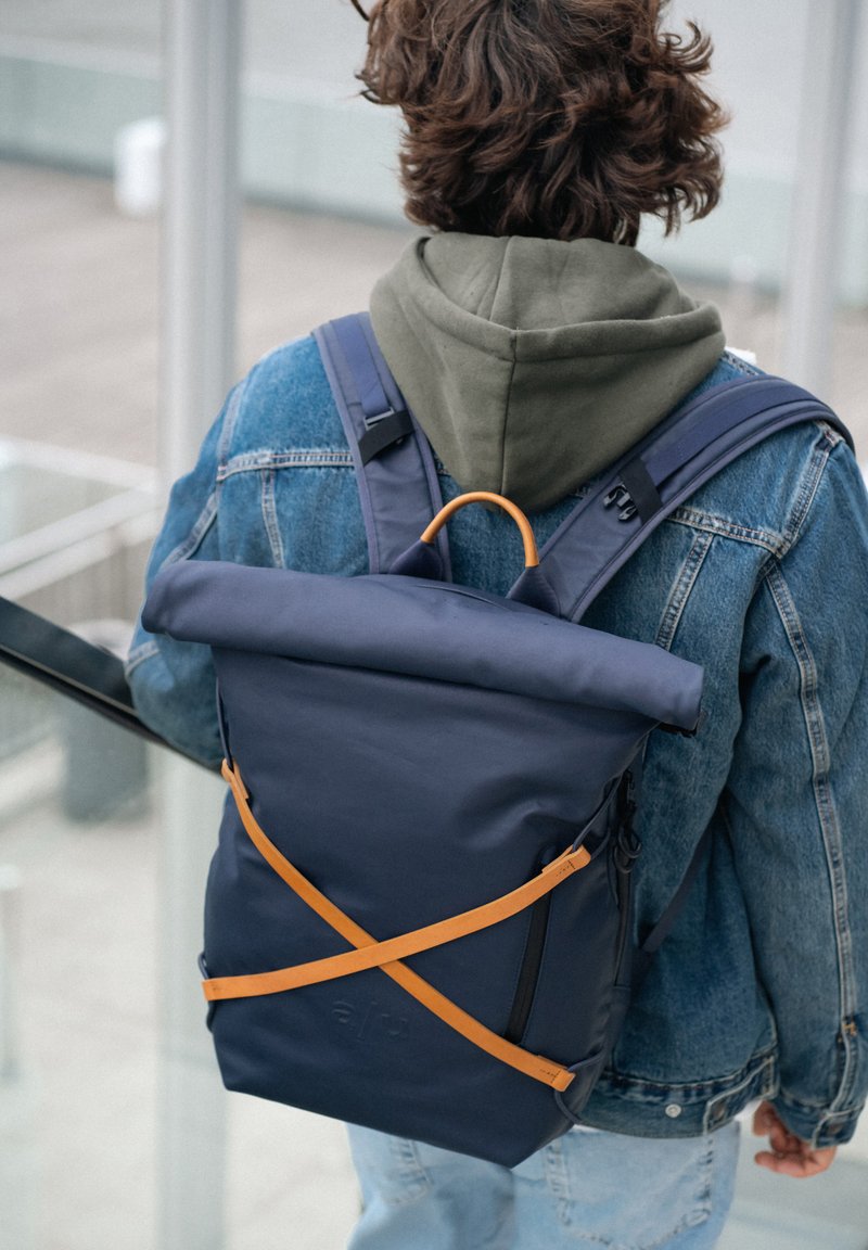 Zaino roll-top della marina realizzato in materiale resistente, con spallacci arancioni e una zip a contrasto, dotato di un design regolabile.
