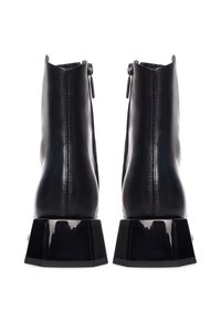 Zwarte leren enkelboots met een hoogglanzende zwarte blokhak en ritssluitingen aan de achterkant. Soepele textuur met minimale stikseldetails.