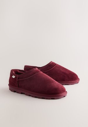 Chaussons bordeaux en tissu doux avec un design discret, présentant une surface texturée et une semelle en caoutchouc robuste.