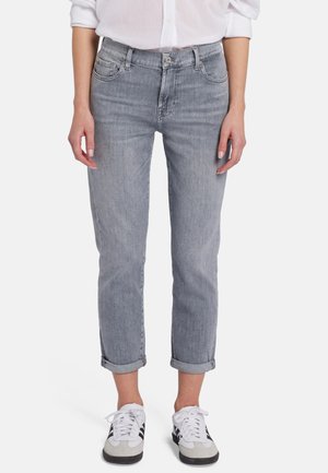 Jean en denim gris clair avec une coupe décontractée, des poignets retroussés et un style classique à cinq poches. Porté avec des baskets noir et blanc.