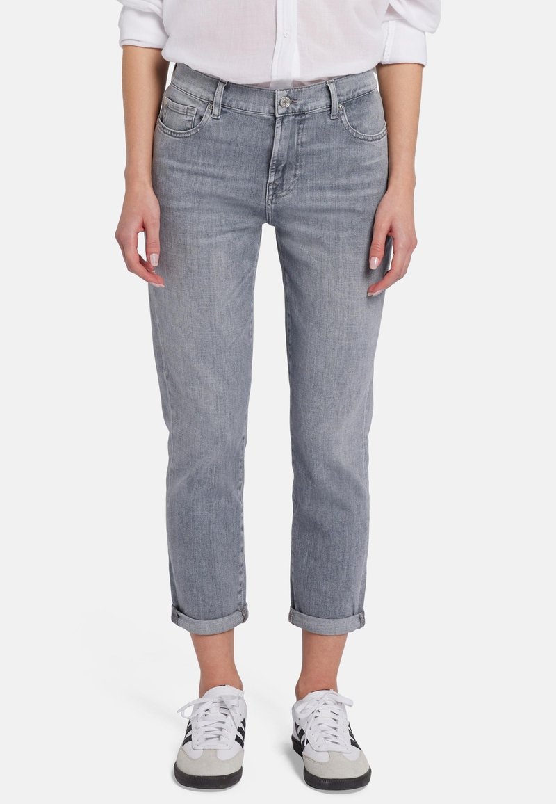 Jean en denim gris clair avec une coupe décontractée, des poignets retroussés et un style classique à cinq poches. Porté avec des baskets noir et blanc.