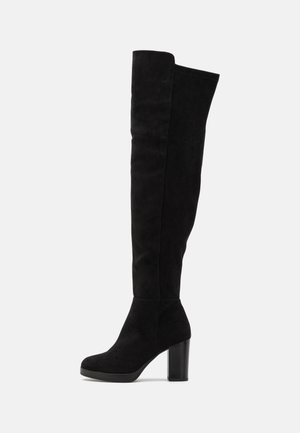 Bottes noires au-dessus du genou en suède avec un talon épais, présentant une texture lisse et un design minimaliste sans quincaillerie visible.