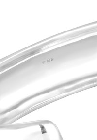 Sterling silverarmband med en slät, reflekterande yta, med stämpelmärken för äkthet. Böjd design med rundade kanter.