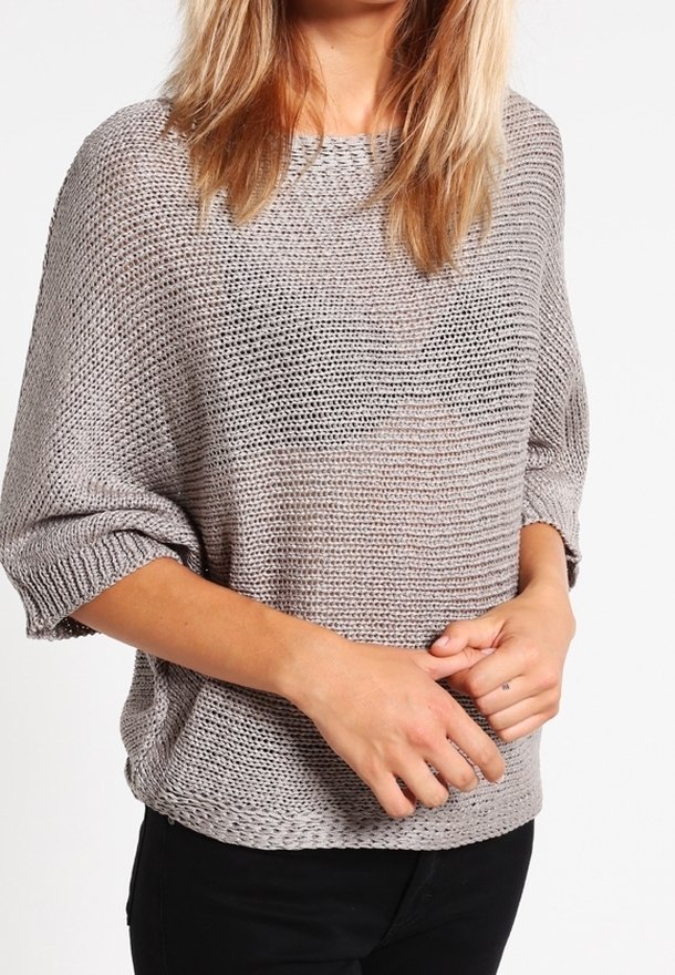 Pull en tricot gris clair avec une coupe ample, un col large et des manches retroussées. La texture est légèrement ajourée, ce qui favorise la respirabilité.