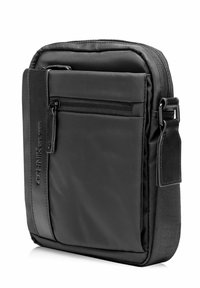 Czarna torba na ramię wykonana z gładkiego nylonu. Posiada przednią kieszeń zamykaną na zamek, regulowany pasek oraz elegancki prostokątny kształt. Casualowa i kompaktowa.