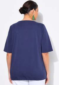 Paarse T-shirt met korte mouwen, ronde halslijn en rechte snit. Gladde textuur, iets losse pasvorm, gestikte zoom en mouwdetails.
