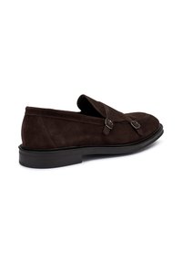 Mocassini in suede marrone con design slip-on, doppia fibbia e tomaia testurizzata, accompagnati da una suola piatta in gomma.