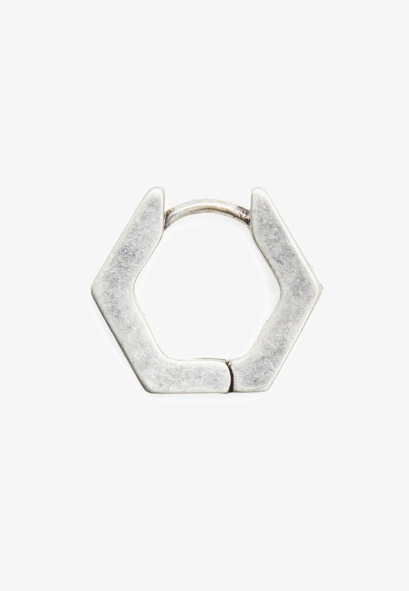 Petit anneau hexagonal en argent avec un fermoir fin en fil courbé sur fond blanc.