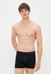 Svarte bomullsbokser med bred elastisk linning. Stoffet er glatt, tettsittende, og har en lett strekk for komfort.