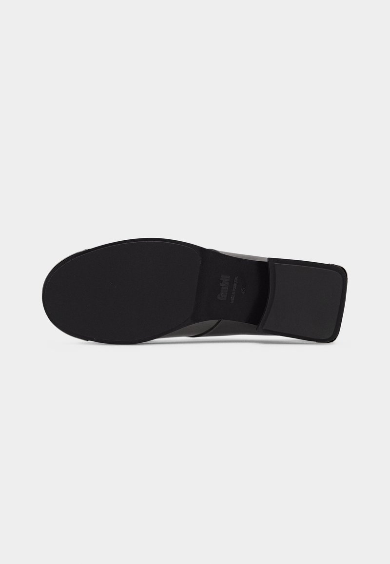 Sole of black formal shoe with square heel, smooth outsole, and brand name embossed near the heel area on a plain gray background.