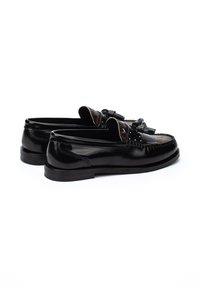 Mocassins en cuir noir avec une finition brillante, des glands décoratifs et un accent en tissu brun texturé. Talon bas et design à bout rond.