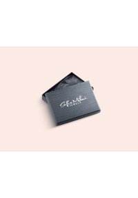 Scatola per gioielli in materiale grigio scuro testurizzato, con un logo bianco per "Sofia Milani Jewels." Il coperchio è leggermente aperto con carta velina nera all'interno.