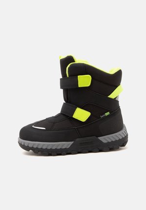 Botte d'hiver noire avec des accents jaune néon, deux sangles réglables, étiquette imperméable et semelle grise épaisse pour usage en extérieur.