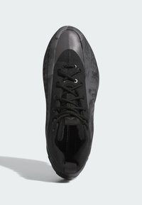 Fekete sportcipő textúrált felsőrésszel, sima szürke orrral és fekete fűzőkkel. Jellemzője a markáns húzófül a sarokrészen.