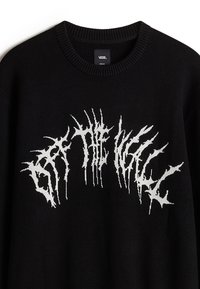 Sudadera de punto negra con cuello acanalado, que presenta un diseño gráfico de texto blanco que parece distorsionado y jagged en el pecho.