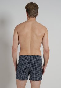 Heren zwembroek in donkerblauw met een wit ruitpatroon. Gemaakt van lichtgewicht materiaal, ze hebben een elastische tailleband en een aansluitend ontwerp.