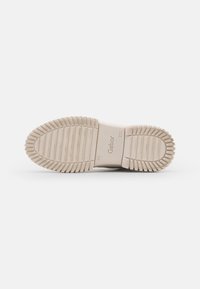 Suela de goma beige con estrías horizontales y verticales, que presenta un logotipo de Gabor elevado. Diseñada para ofrecer comodidad y tracción en diversas superficies.