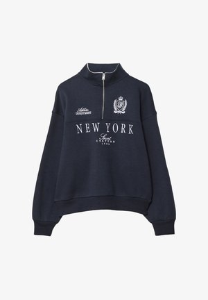 Marineblå sweatshirt med høj krave, halv lynlås og ribbede manchetter. Udstyret med hvid tekst "NEW YORK" og dekorationer på brystet.