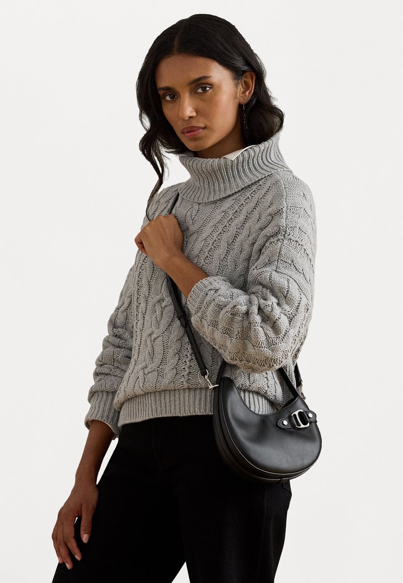 Γκρι πουλόβερ με πλέξη καλωδίου και ψηλό λαιμόκοψη, συνδυασμένο με μια μαύρη τσάντα σε σχήμα ημισέληνου που διαθέτει ασημένια λεπτομέρεια κλεισίματος.